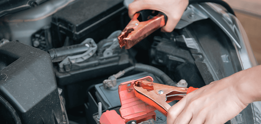 Everything You Need to Know about Your Car Battery at Lancaster Mazda | Person holding battery cables in hand close to the car battery 