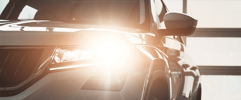 Everything You Need to Know about Your Car Battery at Lancaster Mazda | White SUV with its high beams on its headlights
