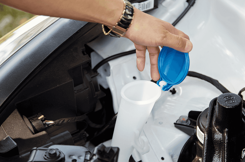 Extend the Life of Your Vehicle at Lancaster Mazda in East Petersburg, PA | Person lifting the lid of windshield washer reservoir to check the level
