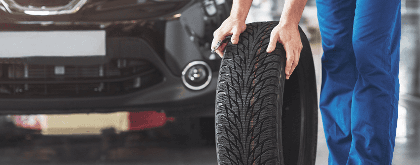 Extend the Life of Your Vehicle at Lancaster Mazda in East Petersburg, PA | Man in blue pants is rolling a used tire on the ground with both his hands