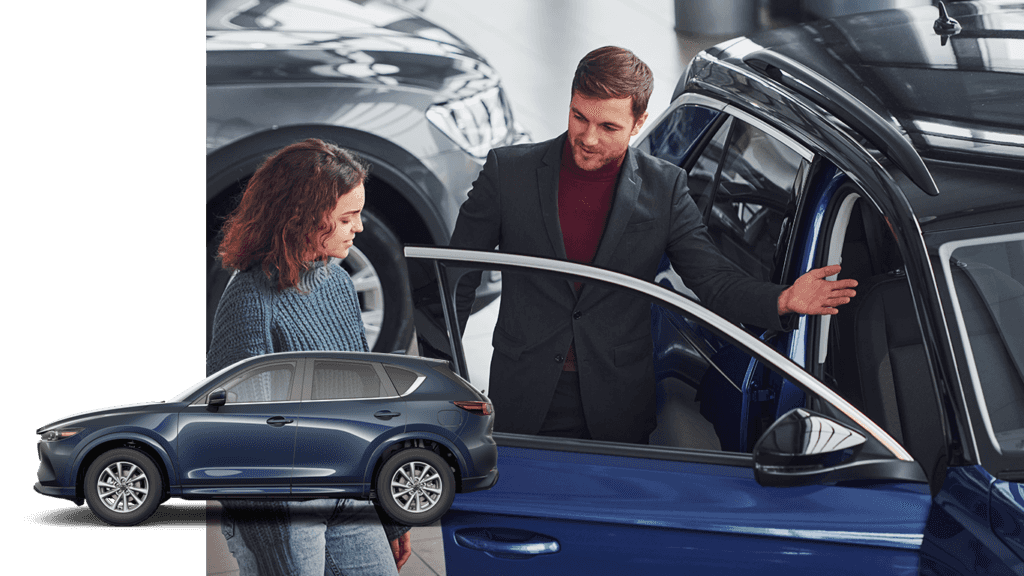Best Time To Buy At Lancaster Mazda in Lancaster, PA | Sales person showing the interior of a navy blue car to woman   