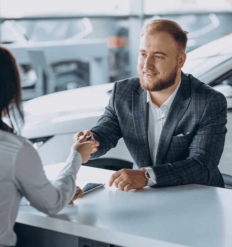 Defining GAP Insurance at Lancaster Mazda in Lancaster, PA | Sales person in suit is handing over car keys to new car owner