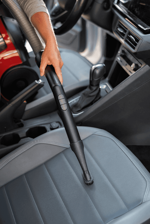 Accessories that help keep your Mazda protected at Lancaster Mazda in East Petersburg, PA | Person using a vacum hose to clean any dirt off his car seats
