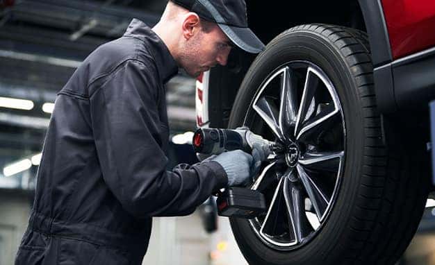 3 Main Benefits of Using OEM parts for your vehicle at Lancaster Mazda in East Petersburg, PA | Mazda mechanic removing wheel off of a Mazda vehicle
