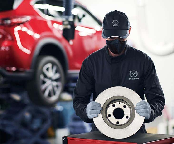 3 Main Benefits of Using OEM parts for your vehicle at Lancaster Mazda in East Petersburg, PA | Mazda mechanic in uniform holding a new brake disc