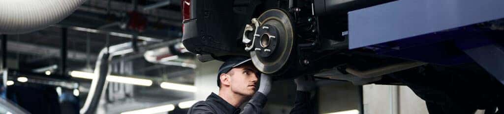 Brake replacement and Safety at Lancaster Mazda | Mechanic inspecting around the rear brakes