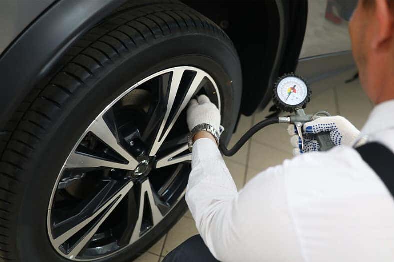 Tire Pressure Information at Lancaster Mazda in East Petersburg, PA | Machaninc using tire pressure tool to put air into tires