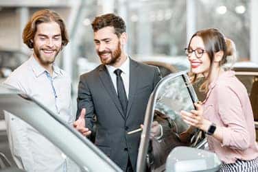 Vehicle Registration Taxes and Fees at Lancaster Mazda in East Petersburg, PA | Sales associate in suit showing customers a car inside of dealership