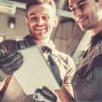 two service technicians looking at checklist while repairing a vehicle