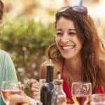 Group of friends gathered around a table, enjoying shared food and wine.