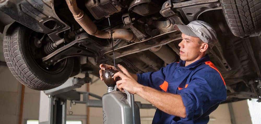 Male mechanic draining the oil from a vehicle during an oil change