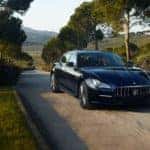 Black Maserati Quattroporte driving along a tree-lined road