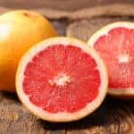 whole and sliced grapefruit on wood background