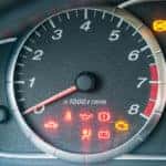 Closeup of car tachometer with many illuminated indicators