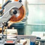 Professional compound mitre circular saw at emnty woodcraft carpentry workshop. DIY carpenter woodworks background. Electric power tools machinery equipment. Safety covered steel jigsaw blade.