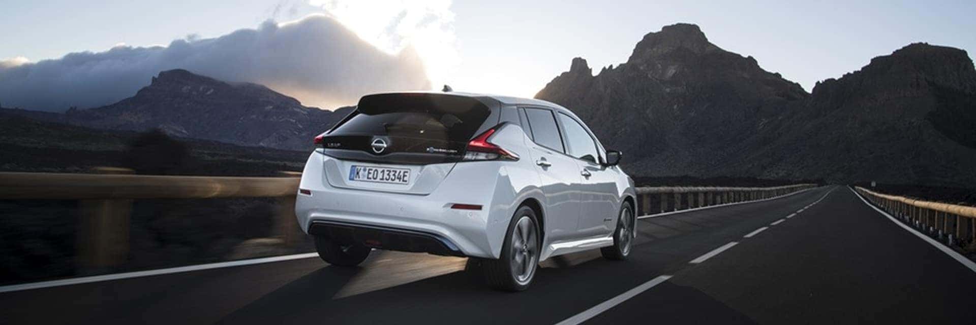 2025 nissan leaf driving on road with mountains in the background