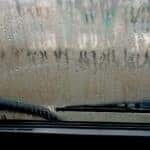 Fogged-up car windshield covered in condensation with windshield wipers visible