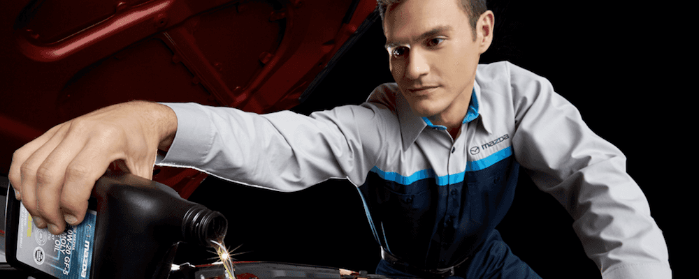 Mazda technician pouring oil into oil filter