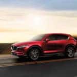 Mazda CX-5 driving on a road in front of the sunset