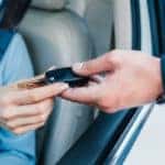Hands passing keys through a car window
