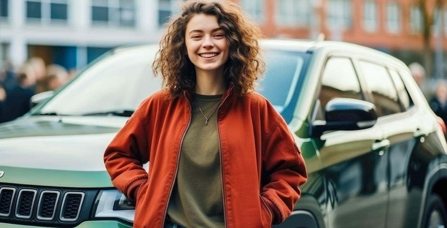 Teenage girl proud of auto financing success, with new car and driver's license.