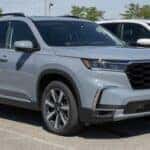 A shiny new Honda Pilot SUV parked prominently on the showroom floor of a dealership, with promotional banners in the background and a salesperson nearby ready to assist potential buyers.