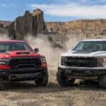 red RAM RHO and white FORD Raptor in the desert.