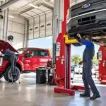 Technicians inspecting used Ford trucks in a service bay