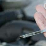 Hand holding engine oil dipstick to check level