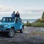 Jeep Wrangler JK parked off-road with couple leaning on it.