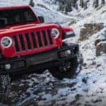Jeep Wrangler driving up snowy cliffside